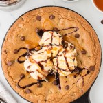 Freshly baked chocolate chip pizookie served in a cast iron skillet, topped with vanilla ice cream, drizzled with hot fudge and caramel sauce.