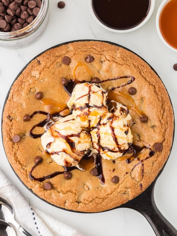 Freshly baked chocolate chip pizookie served in a cast iron skillet, topped with vanilla ice cream, drizzled with hot fudge and caramel sauce.