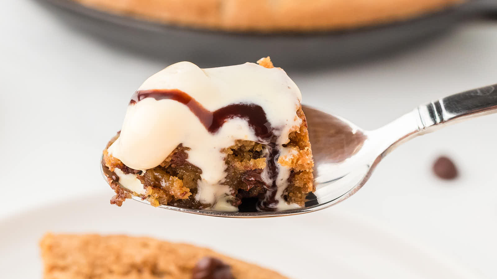 Spoonful of warm chocolate chip Pizookie topped with melting vanilla ice cream and a drizzle of hot fudge.