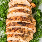 Juicy Roasted Turkey sliced and arranged on a platter with fresh parsley and herbs.