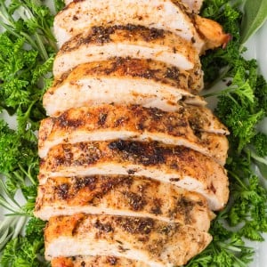 Juicy Roasted Turkey sliced and arranged on a platter with fresh parsley and herbs.