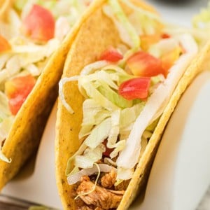 Hard shell taco filled with leftover turkey, shredded lettuce, and diced tomatoes, served in a taco holder.