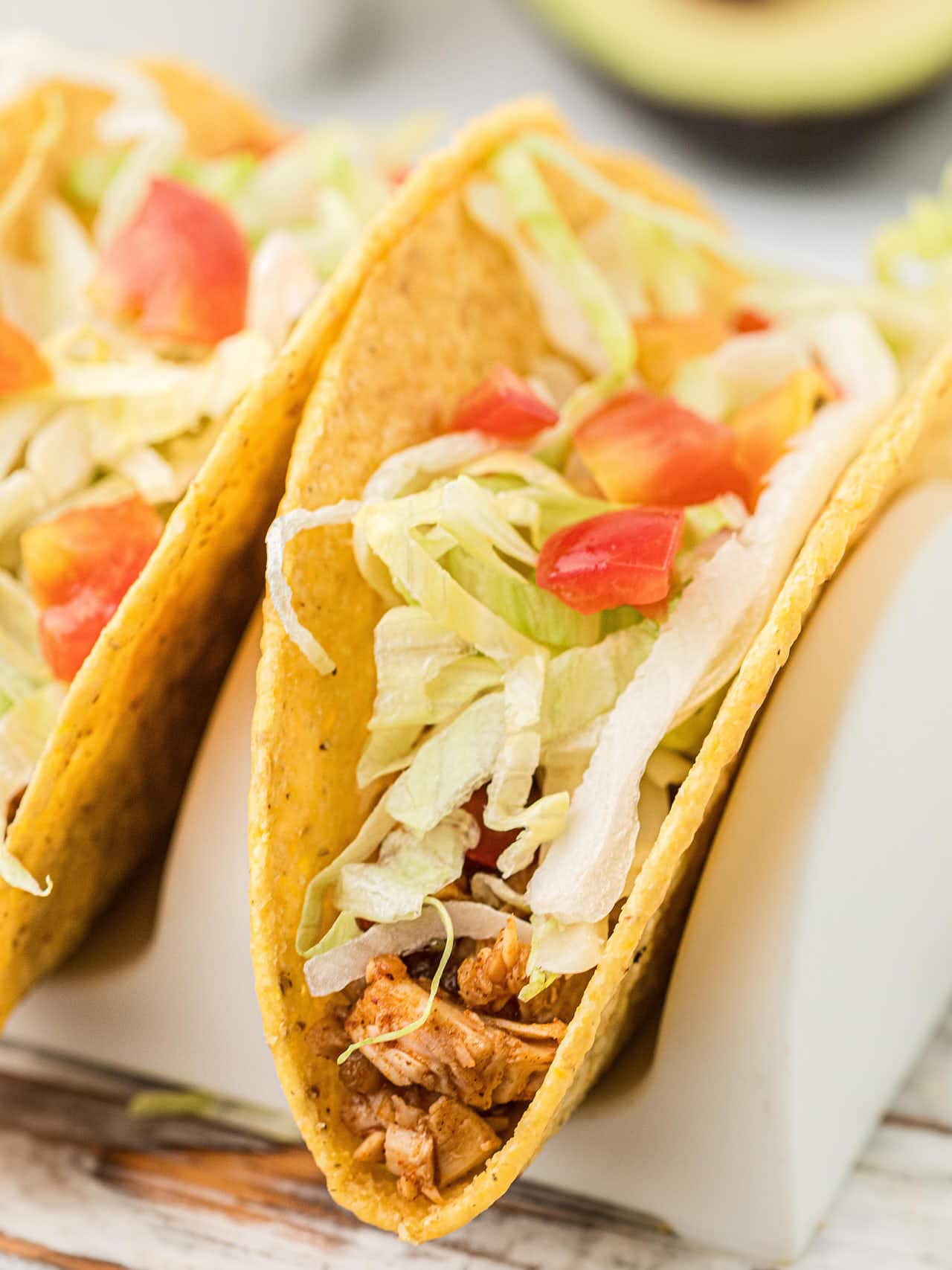 Hard shell taco filled with leftover turkey, shredded lettuce, and diced tomatoes, served in a taco holder.