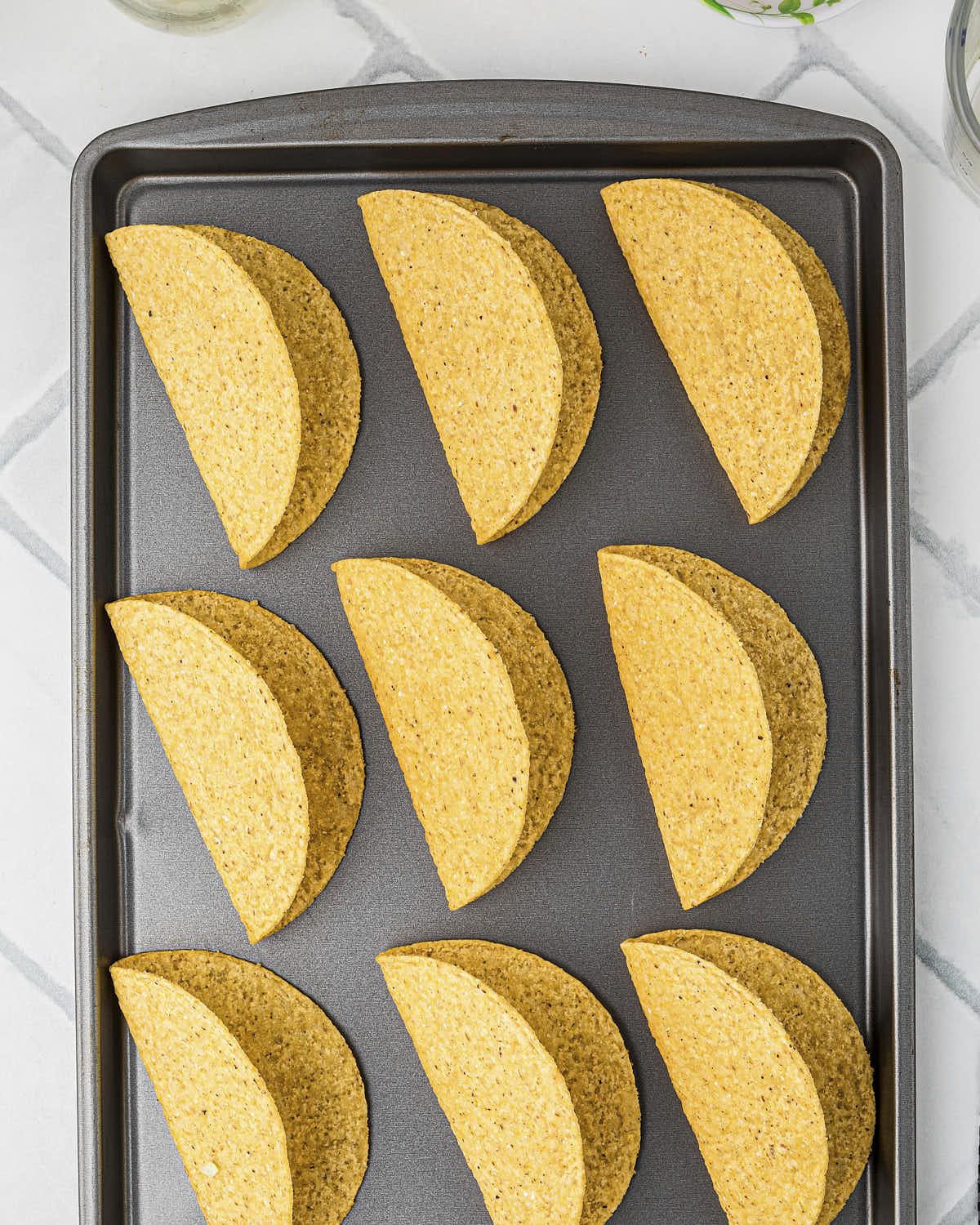 Hard shell tacos on a baking sheet.
