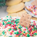 Christmas Dip topped with red, green, and gold sprinkles, served with graham crackers and sugar cookies in the background.