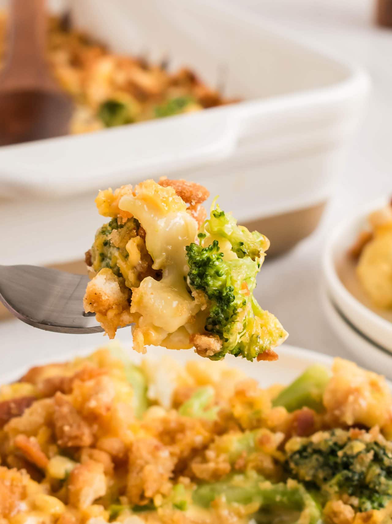 A fork holding a bite of Broccoli Cauliflower Casserole with melted cheese and buttery stuffing topping.
