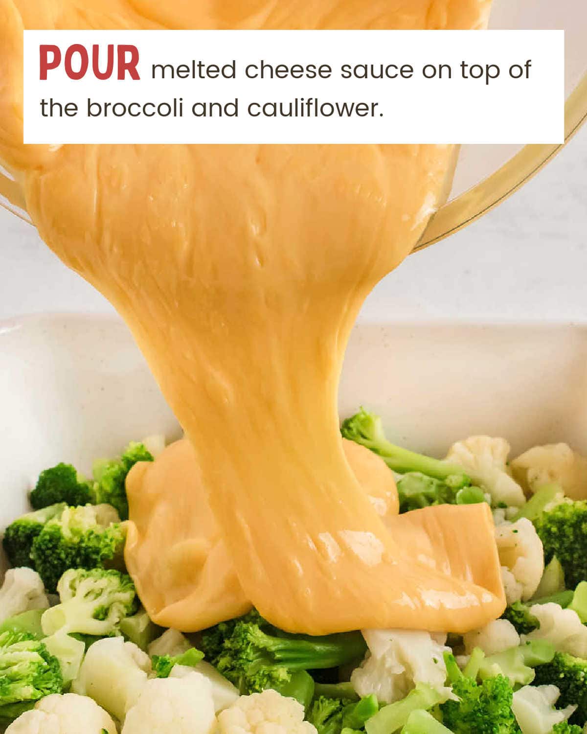 Pouring cheese sauce over the broccoli and cauliflower.