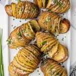 Freshly baked Hasselback Potatoes served on a white plate.
