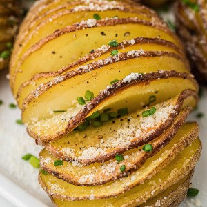 Closeup of a Hasselback Potato on a white plate.