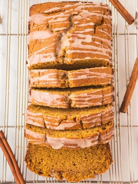 Pumpkin Bread Loaf with icing, sliced on a cooling rack.
