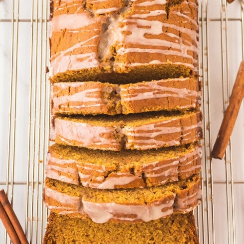 Pumpkin Bread Loaf with icing, sliced on a cooling rack.