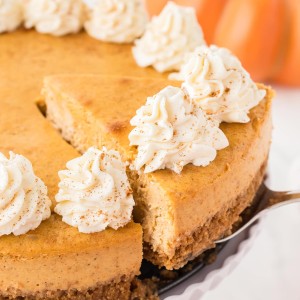 Slice of Pumpkin Cheesecake with whipped cream on a graham cracker crust.