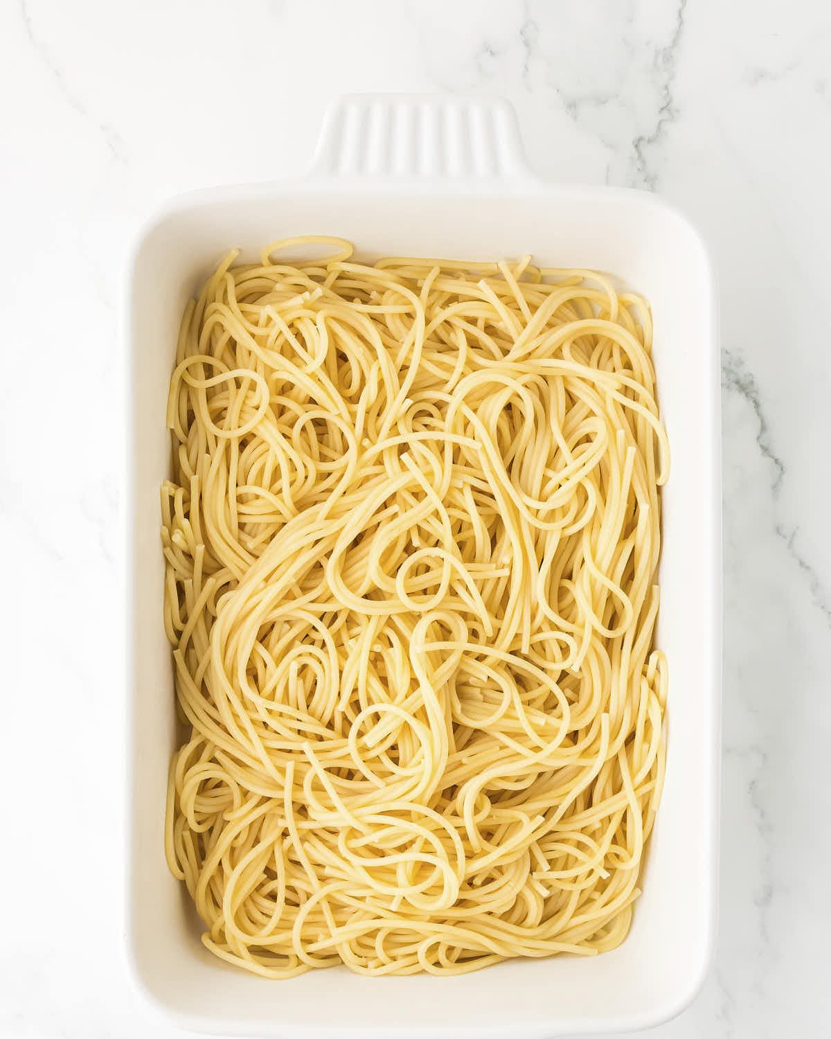 Cooked spaghetti in a casserole dish for easy Turkey Tetrazzini.