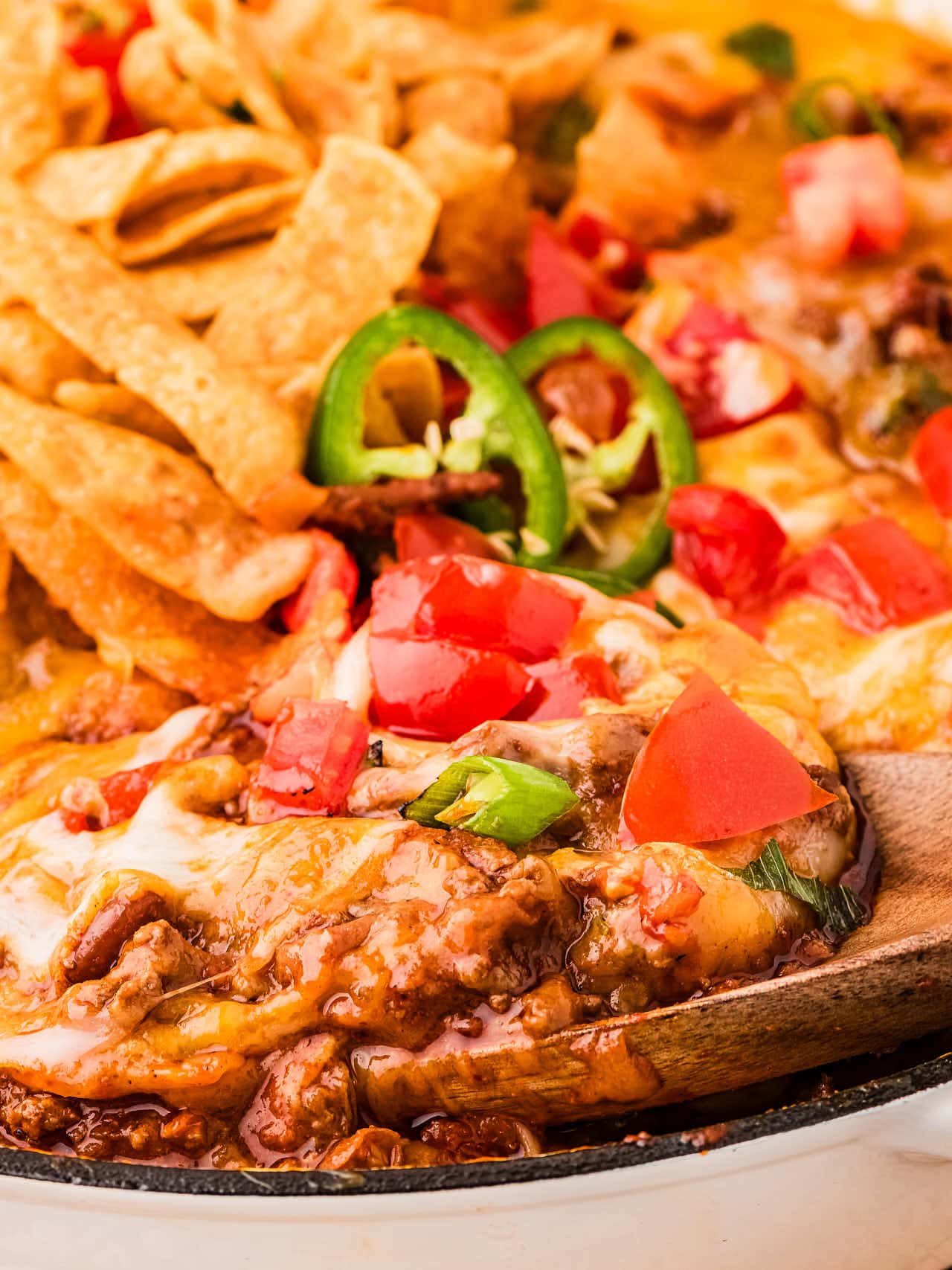 Closeup of a wooden spoon filled with hot Frito Pie.