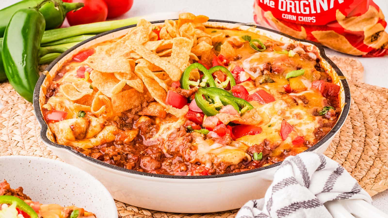 Skillet with Frito Pie topped with Fritos and jalapenos.