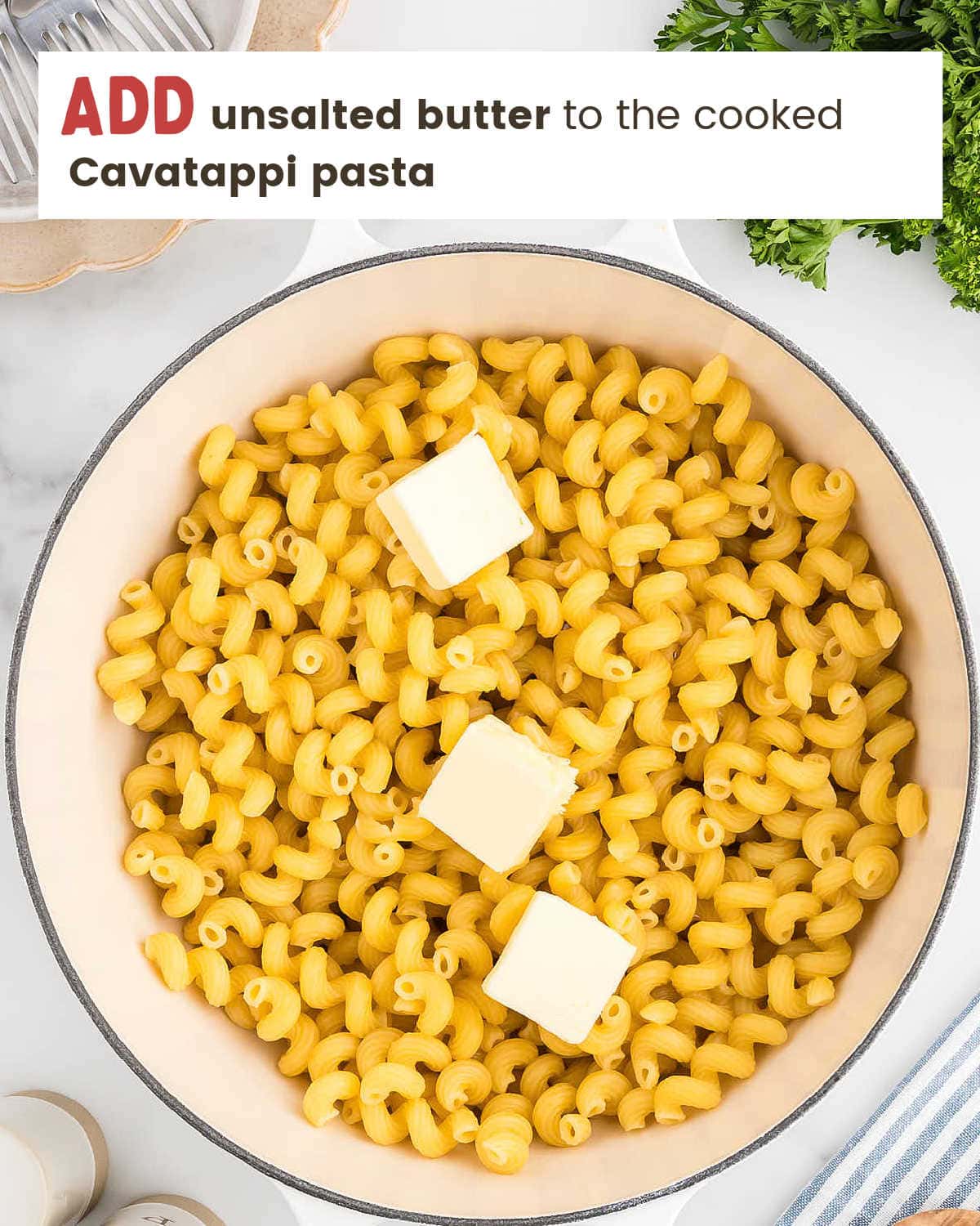 Cooked cavatappi pasta in a pot with sliced butter on top.