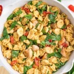 Marry Me Chicken Tortellini in a skillet with creamy sauce, spinach, sun-dried tomatoes, and tender chicken.