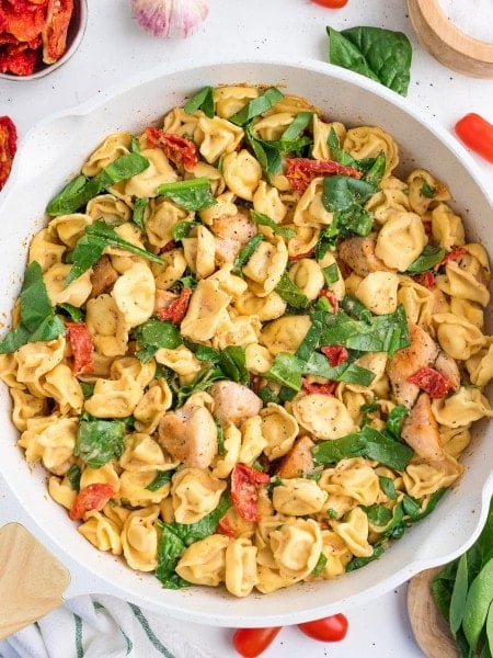 Marry Me Chicken Tortellini in a skillet with creamy sauce, spinach, sun-dried tomatoes, and tender chicken.