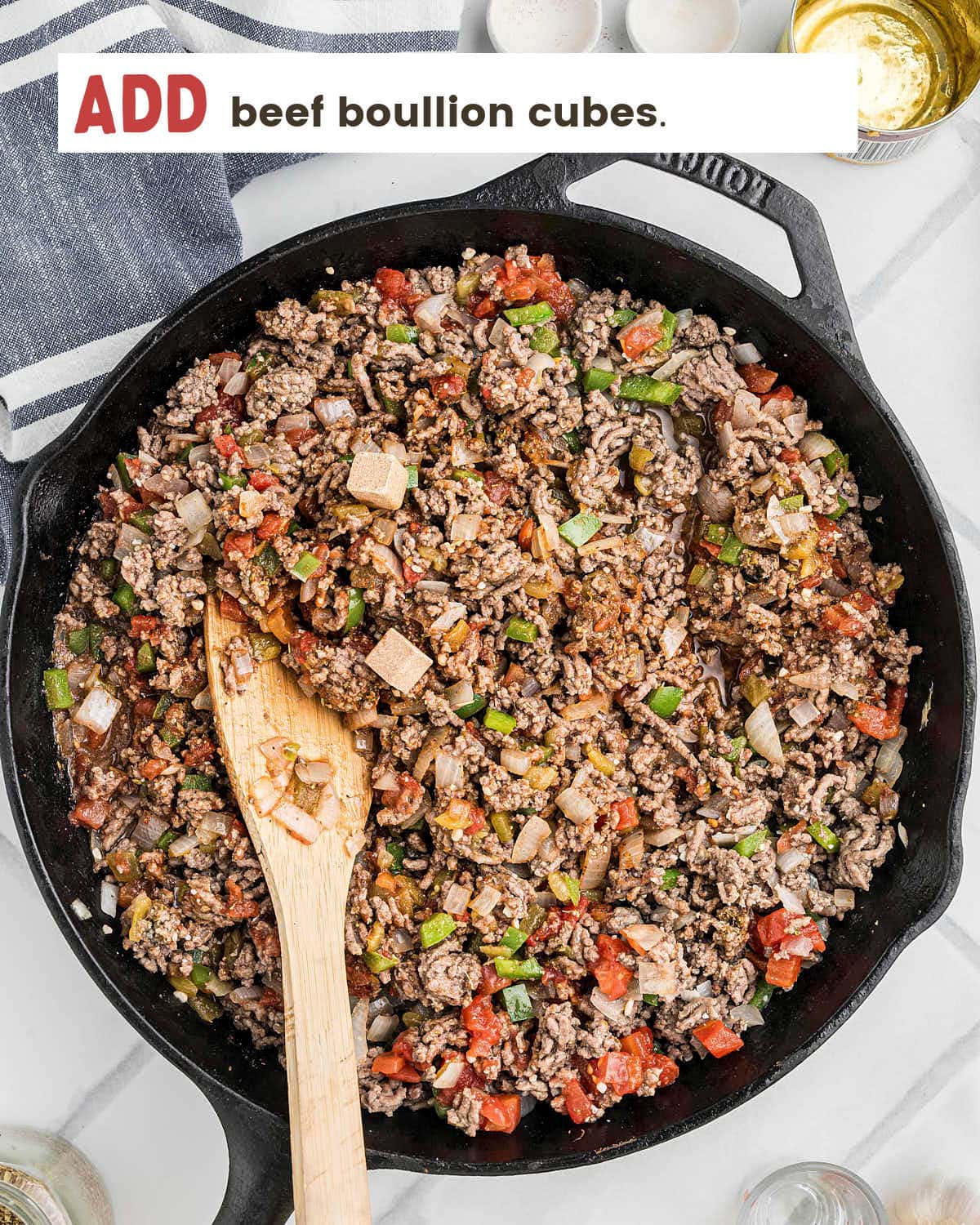 Beef cubes being added to the Picadillo meat mixture.