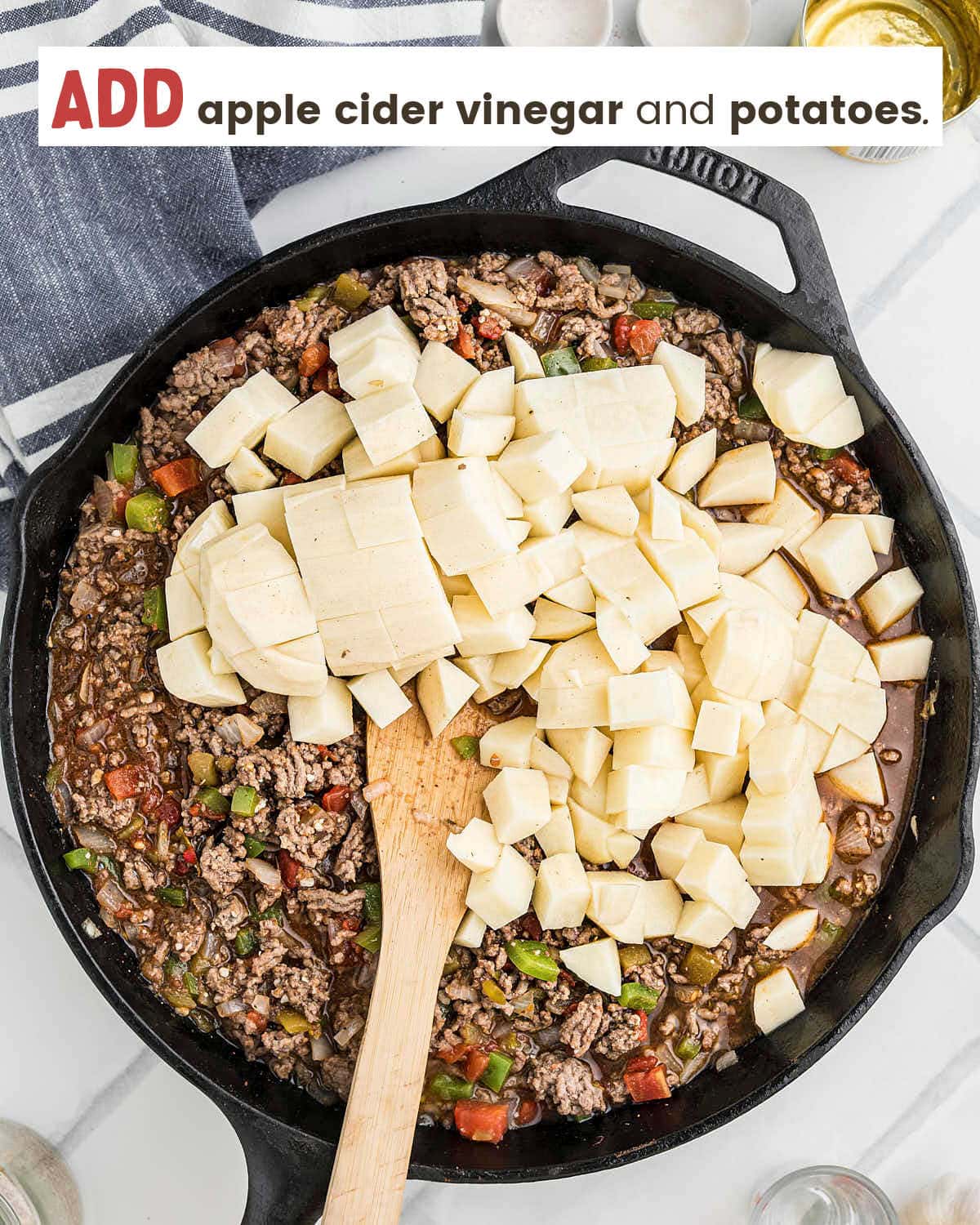 Diced Russet potatoes being added to the Picadillo mixture in the cast iron skillet.