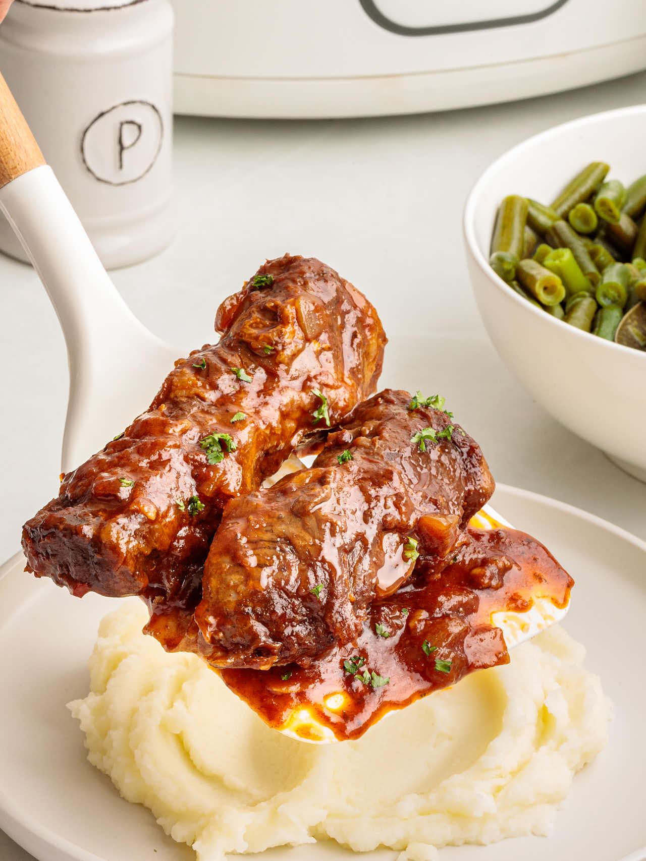 Adding three perfectly cooked Crockpot Boneless Beef Ribs over mashed potatoes.