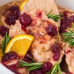 Closeup Cranberry Chicken in the slow cooker with a wooden spatula.
