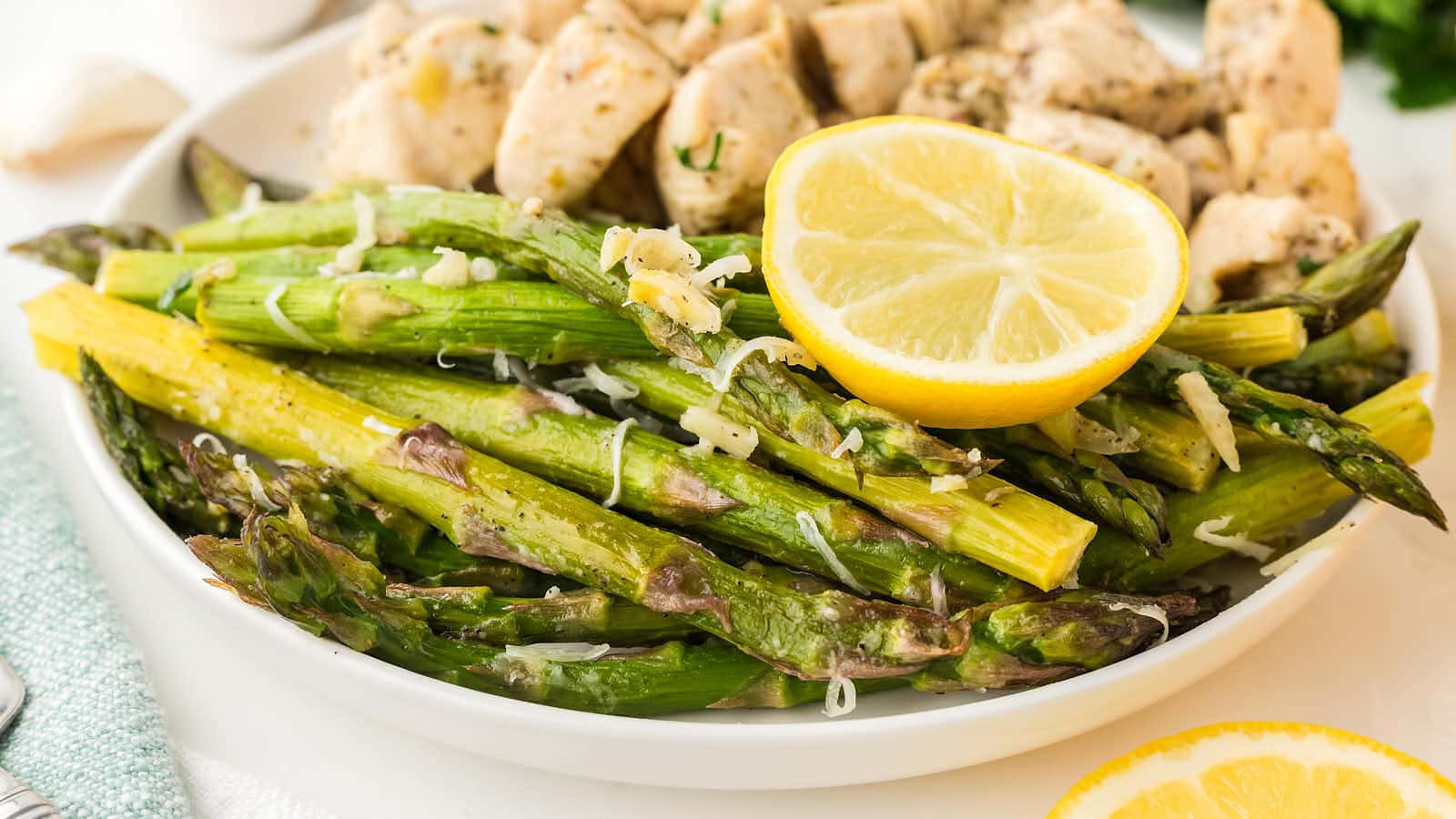 Oven Roasted Asparagus served on a white plate with chicken bites.