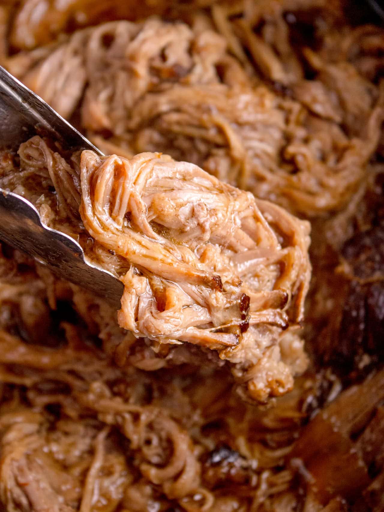Closeup of a tongue transferring the brisket from the slow cooker