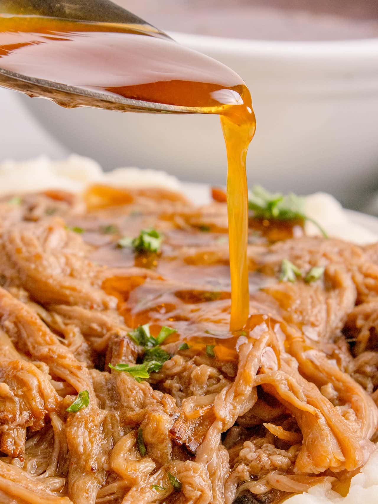 Pouring extra sauce over the brisket with a spoon.
