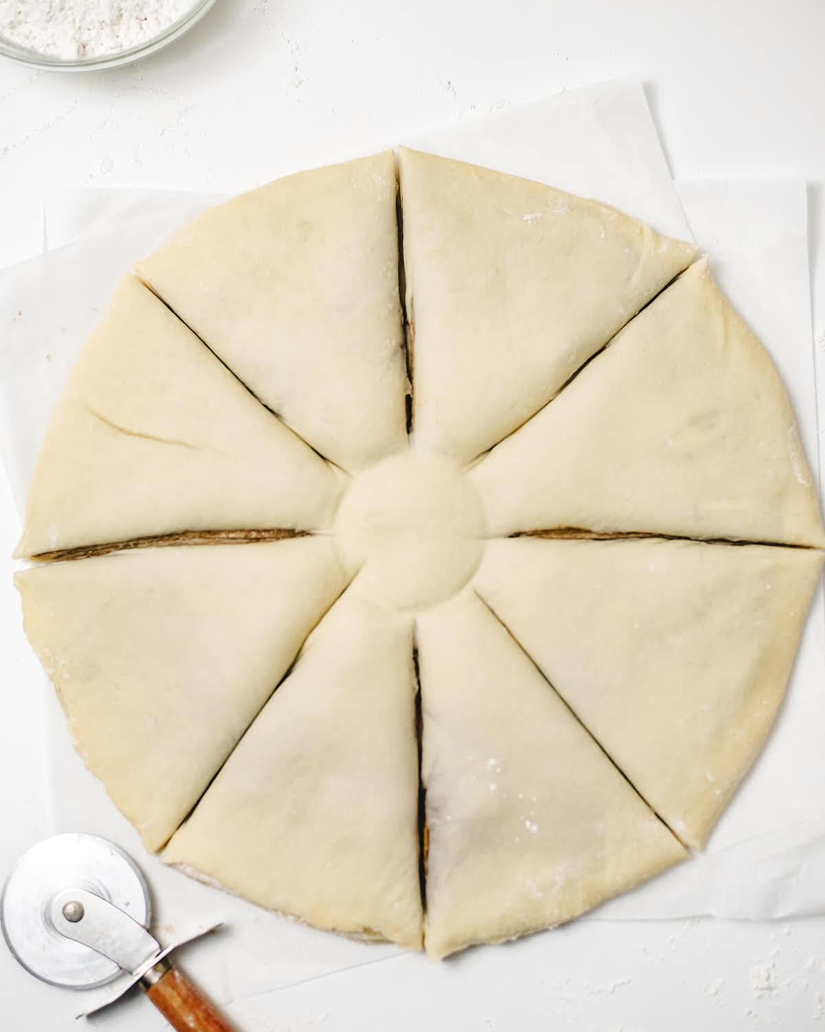 Topping the Nutella layer with another rolled out dough ball and marking 8 indentations.
