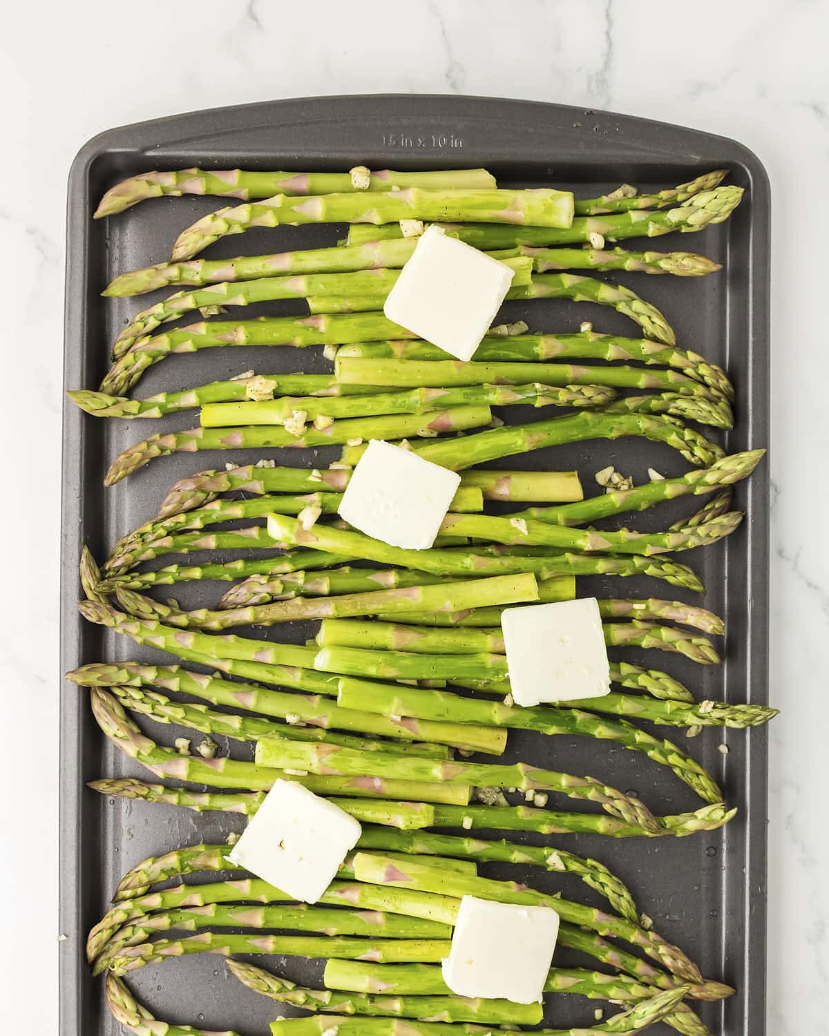 Adding thinly sliced butter over the asparagus.