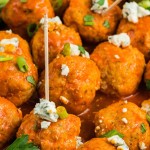 Buffalo Chicken Meatballs on cocktail picks topped with blue cheese crumbles and sliced green onion.
