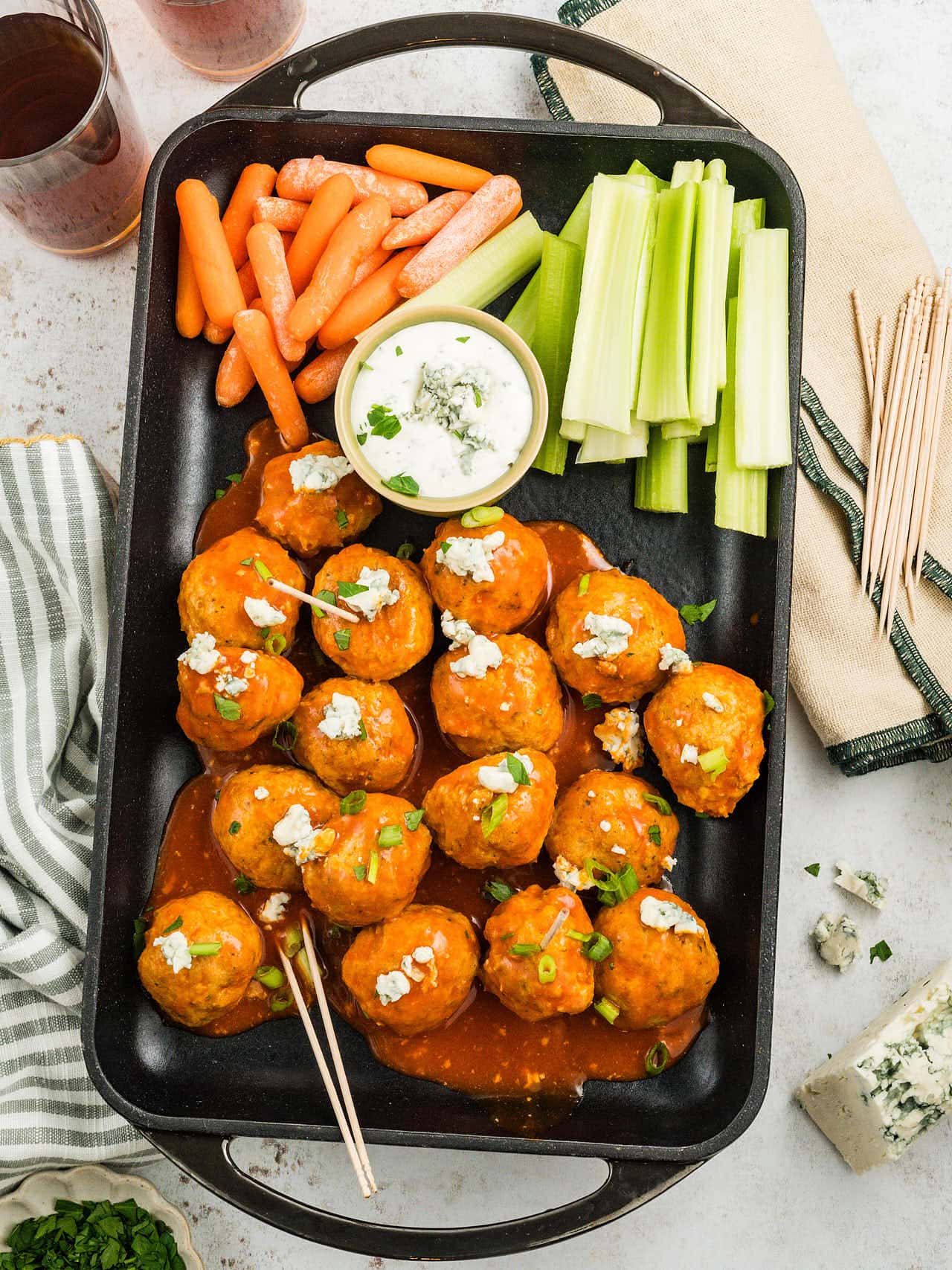 A platter of Buffalo Chicken Meatballs with carrots, celery, blue cheese dip, and cocktail picks.