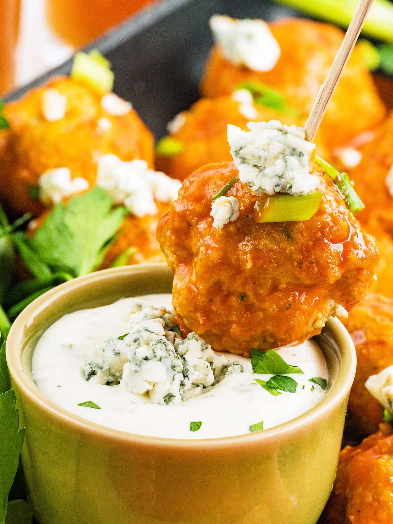 A Buffalo Chicken Meatball on a pick dipped into creamy blue cheese dip.