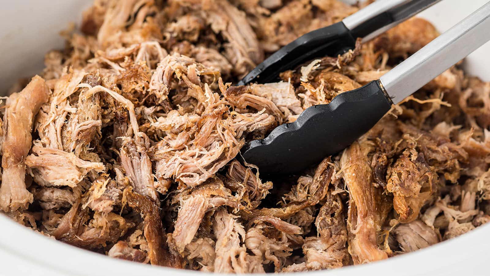 Tender shredded pork carnitas in a slow cooker ready to serve.