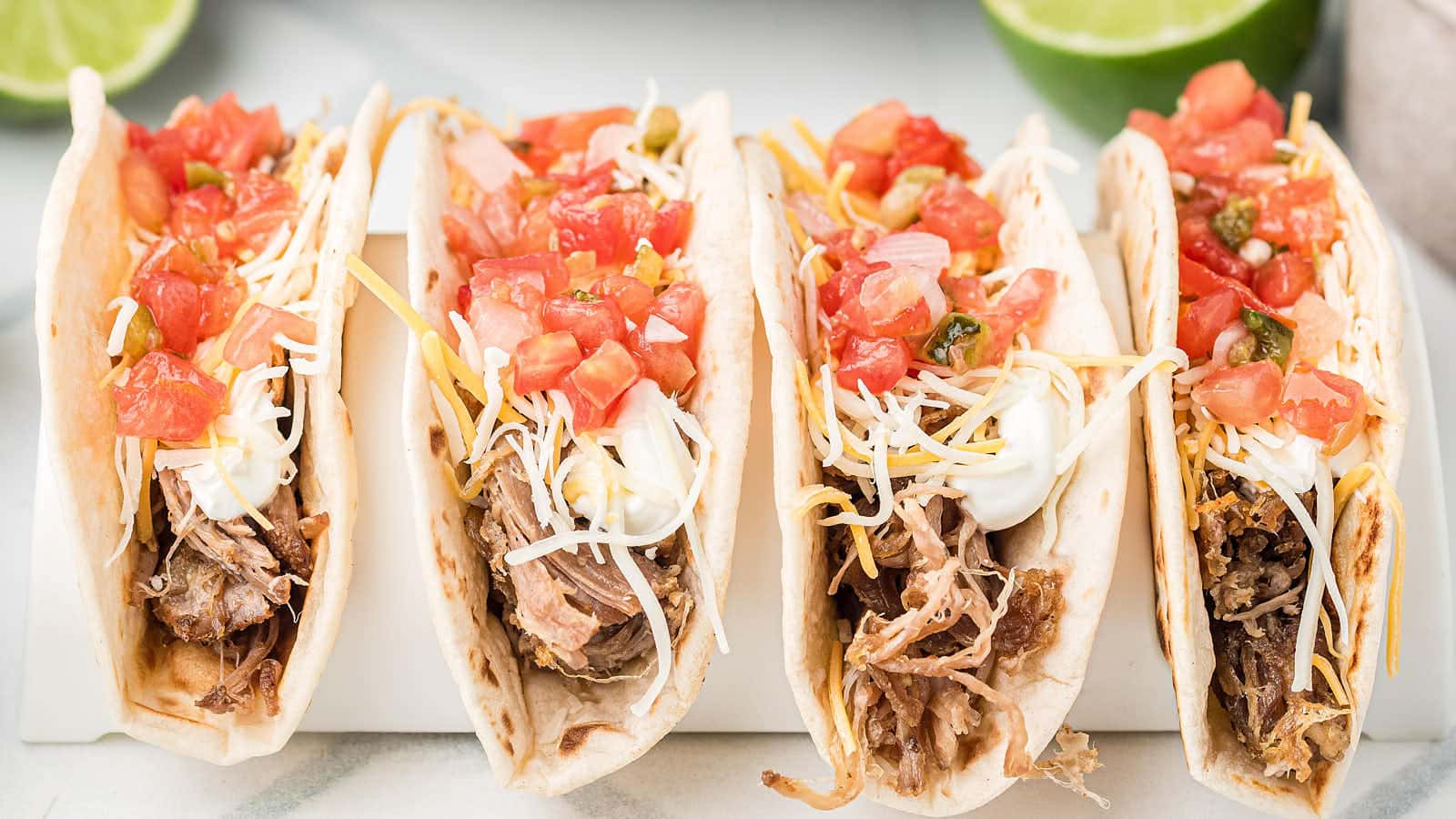 Slow cooker carnitas served in soft tacos with fresh toppings.