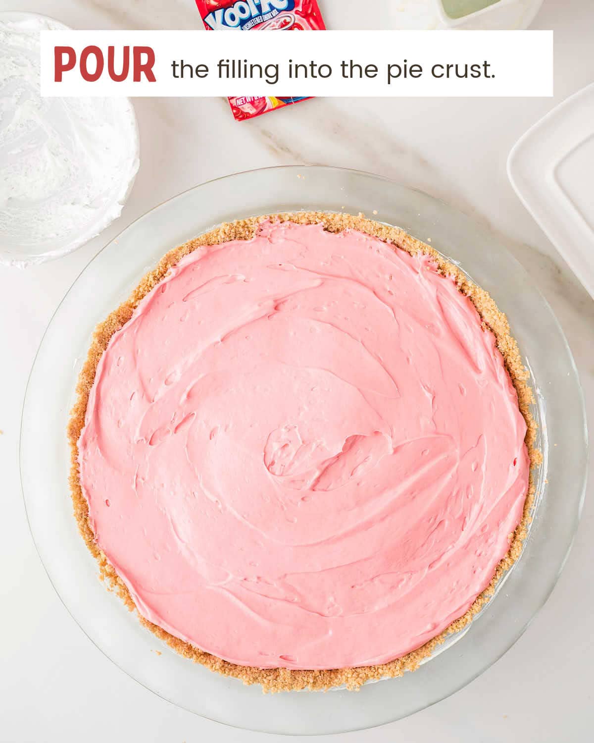 Pink Kool Aid Pie filling spread into a graham cracker crust before chilling.