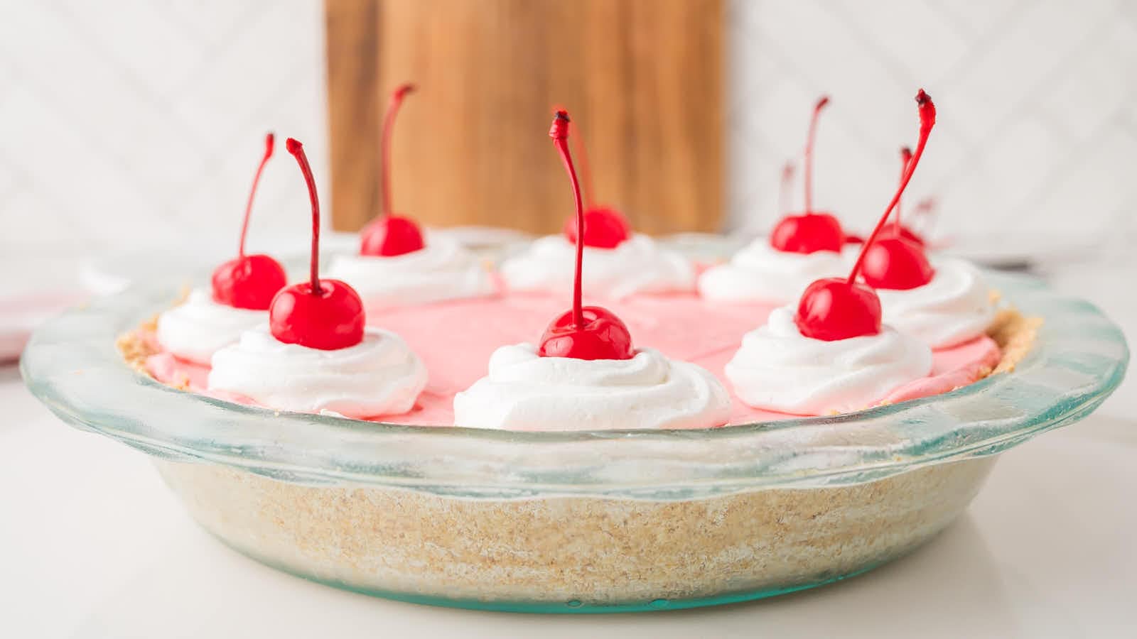 Side view of kool aid pie in a glass dish showing the graham cracker crust and pink filling.