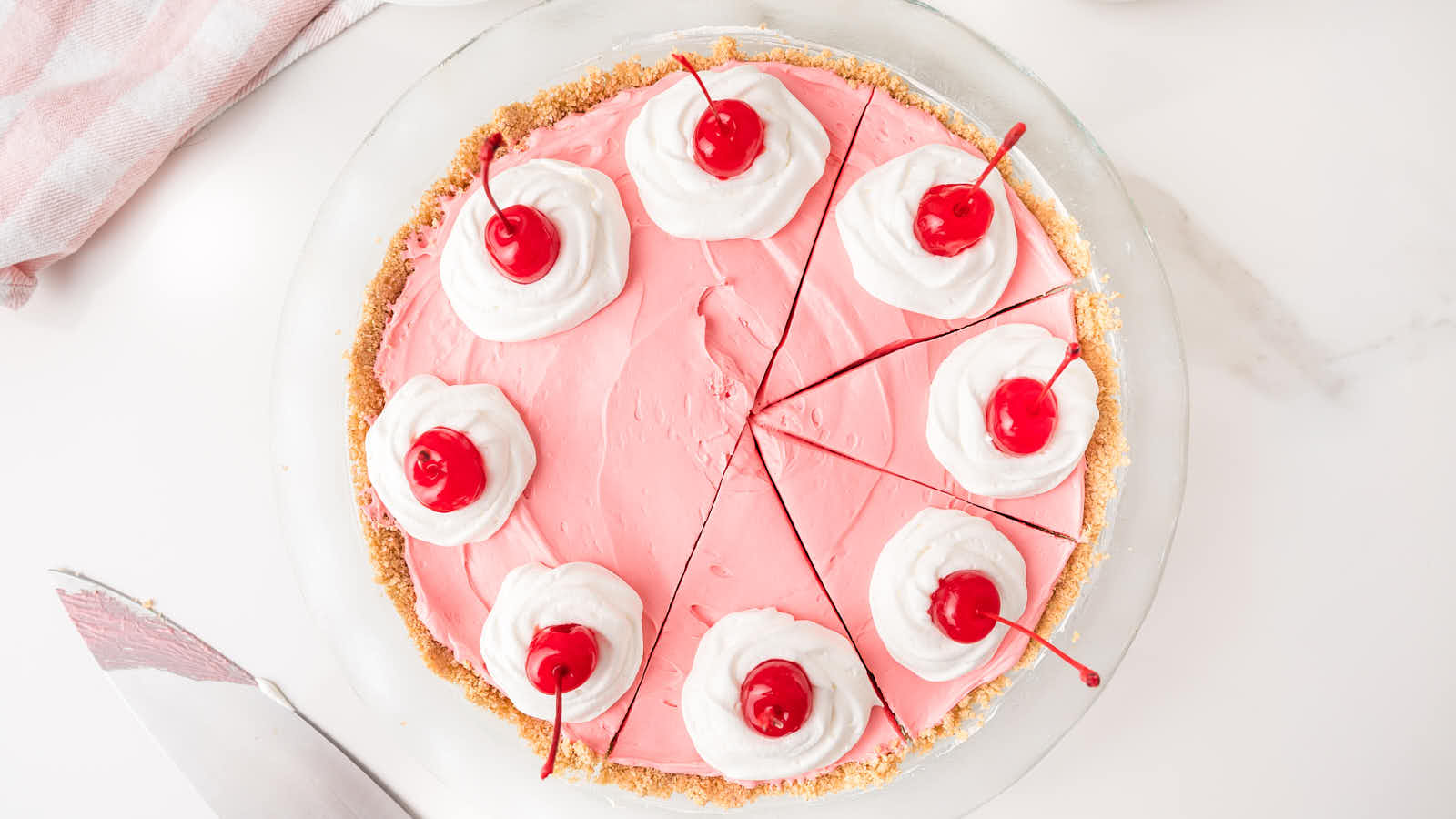 Slice of kool aid pie on a plate with a fork bite taken showing the creamy pink filling.