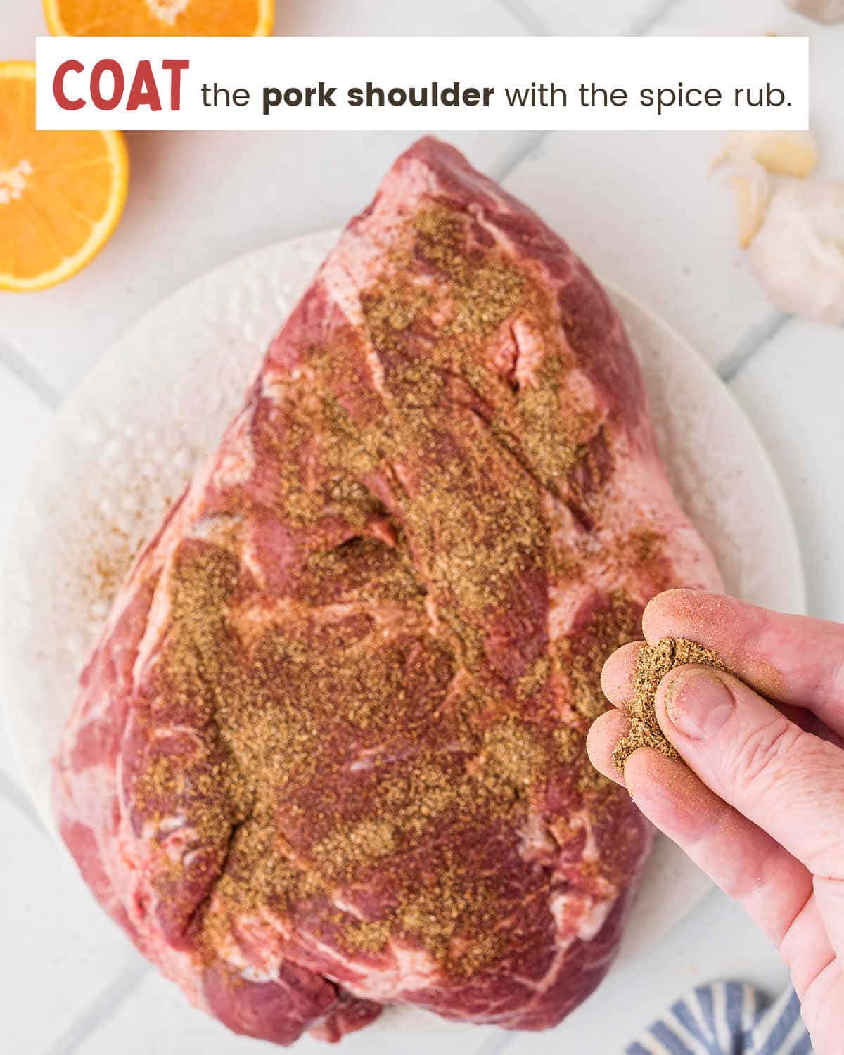 Seasoning a pork shoulder with the spice rub.