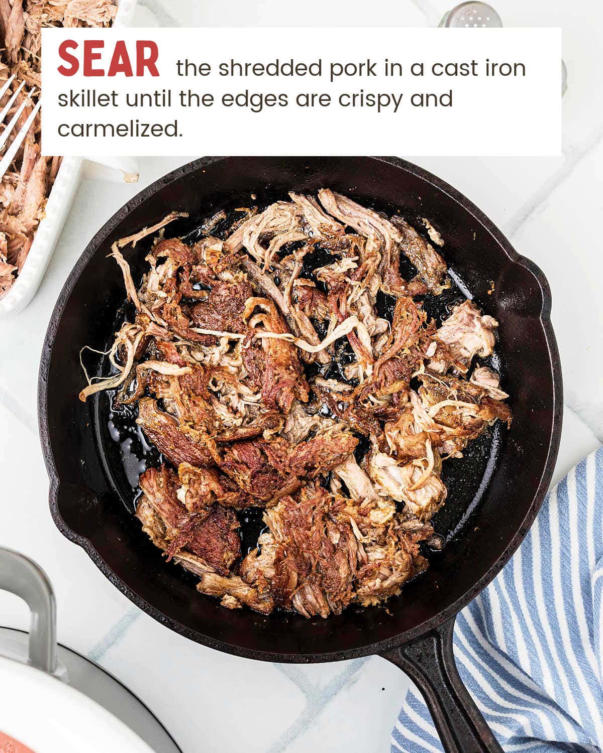 Shredded pork carnitas crisping in a hot cast iron skillet.