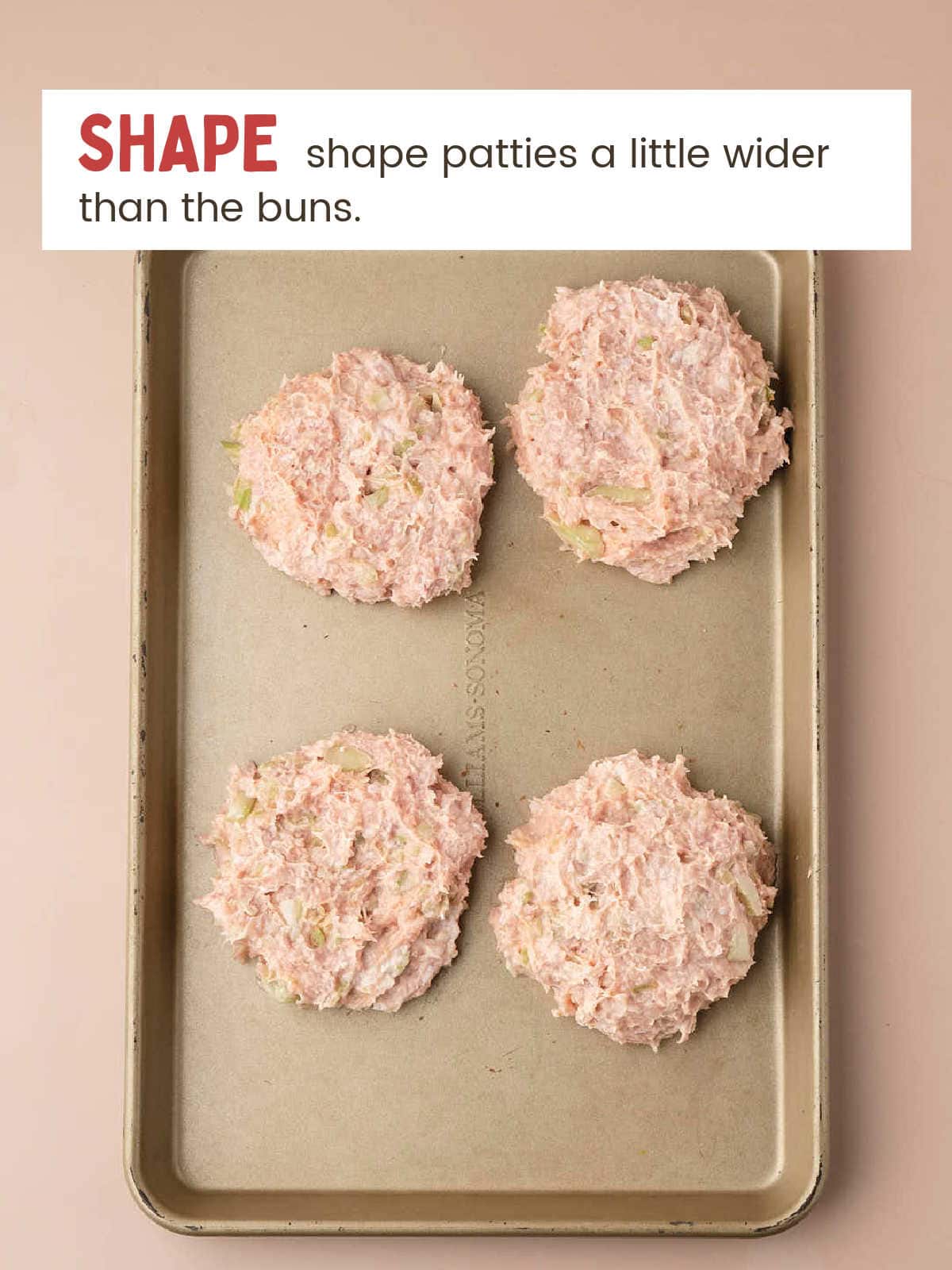 Four raw Buffalo Chicken Burger patties shaped on a baking sheet before baking.