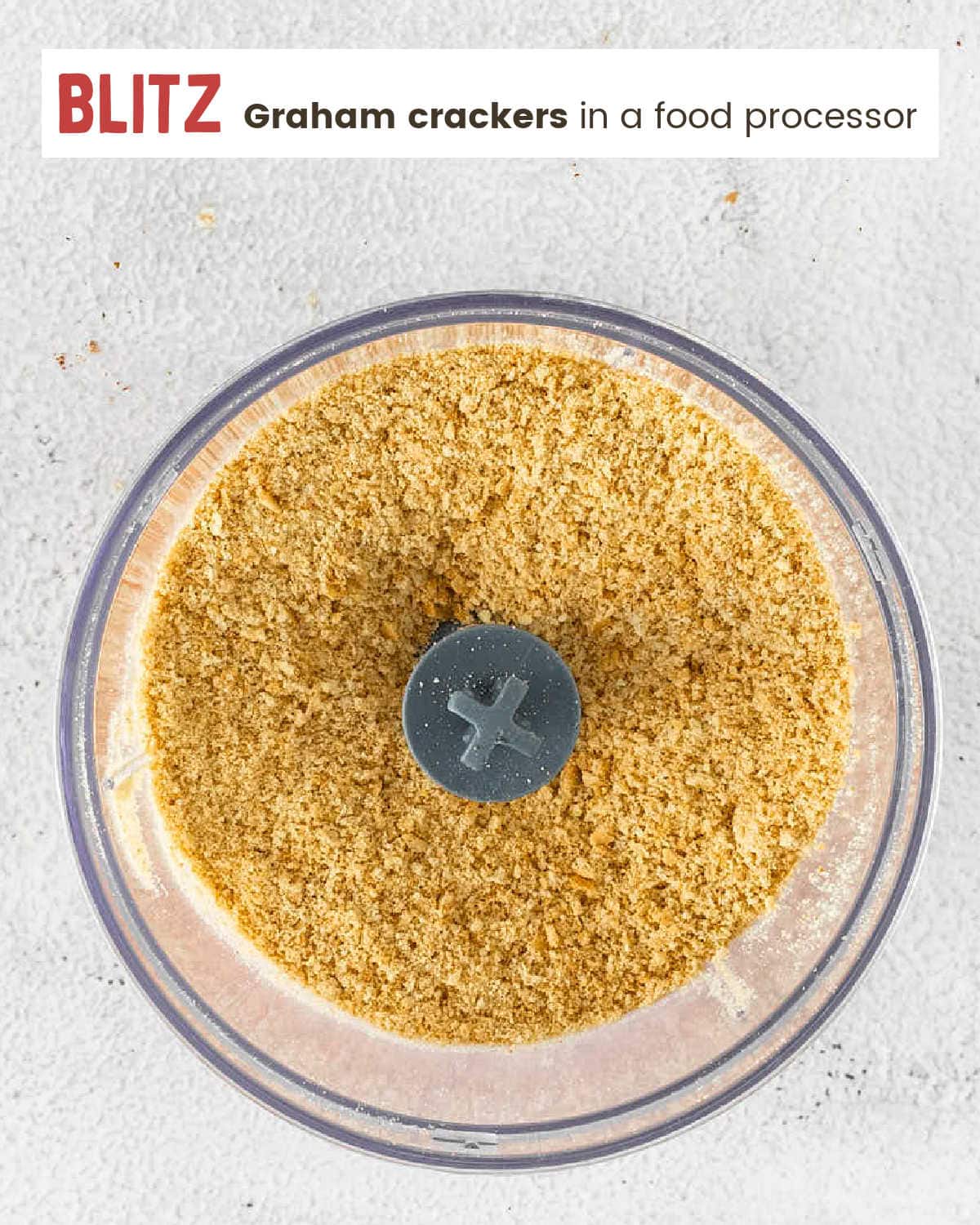 Graham cracker crumbs ground fine in a food processor bowl.