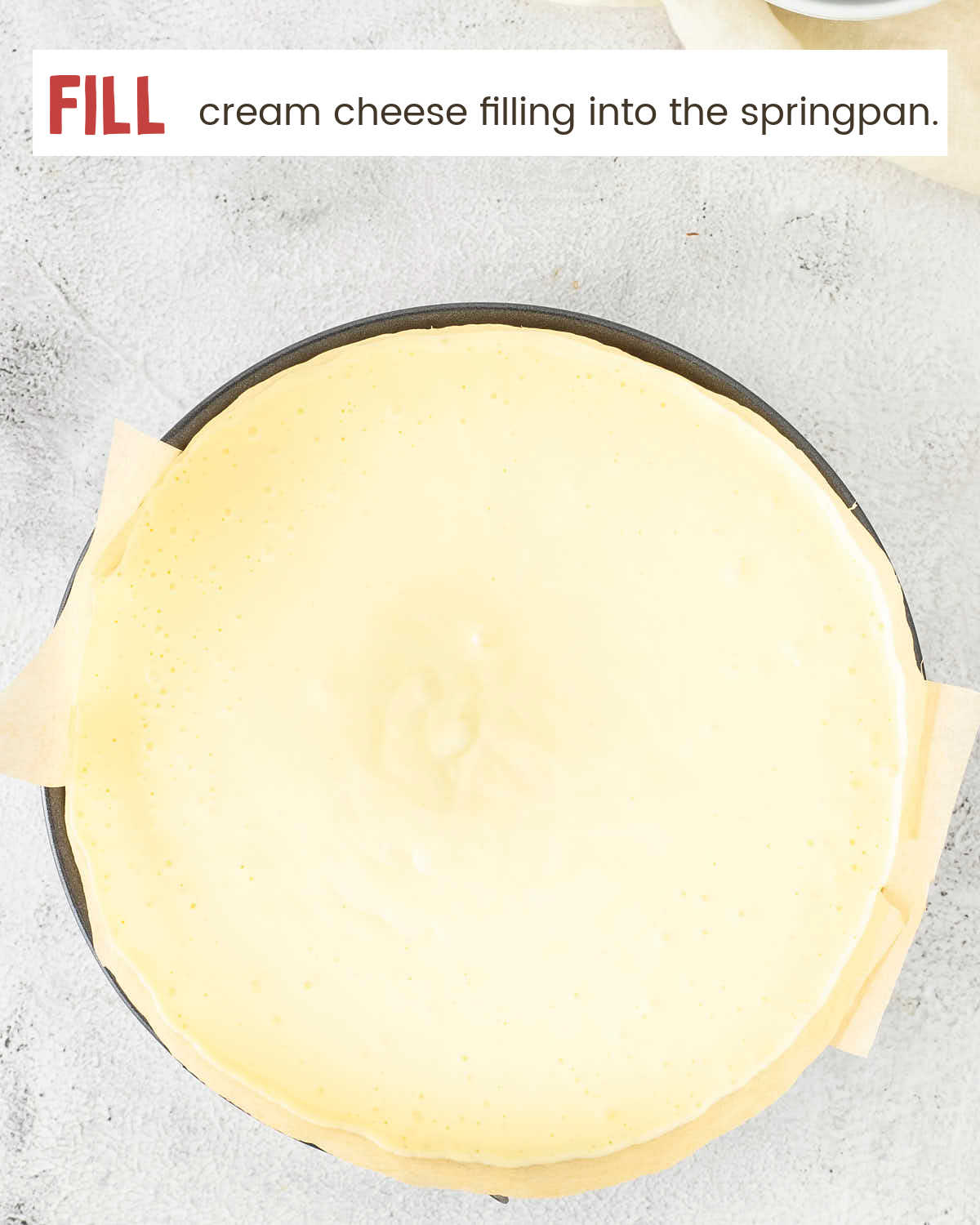 Smooth cheesecake filling poured into a parchment-lined springform pan before baking.