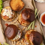 Overhead view of Buffalo Chicken Burgers on a sheet pan with fries and celery.