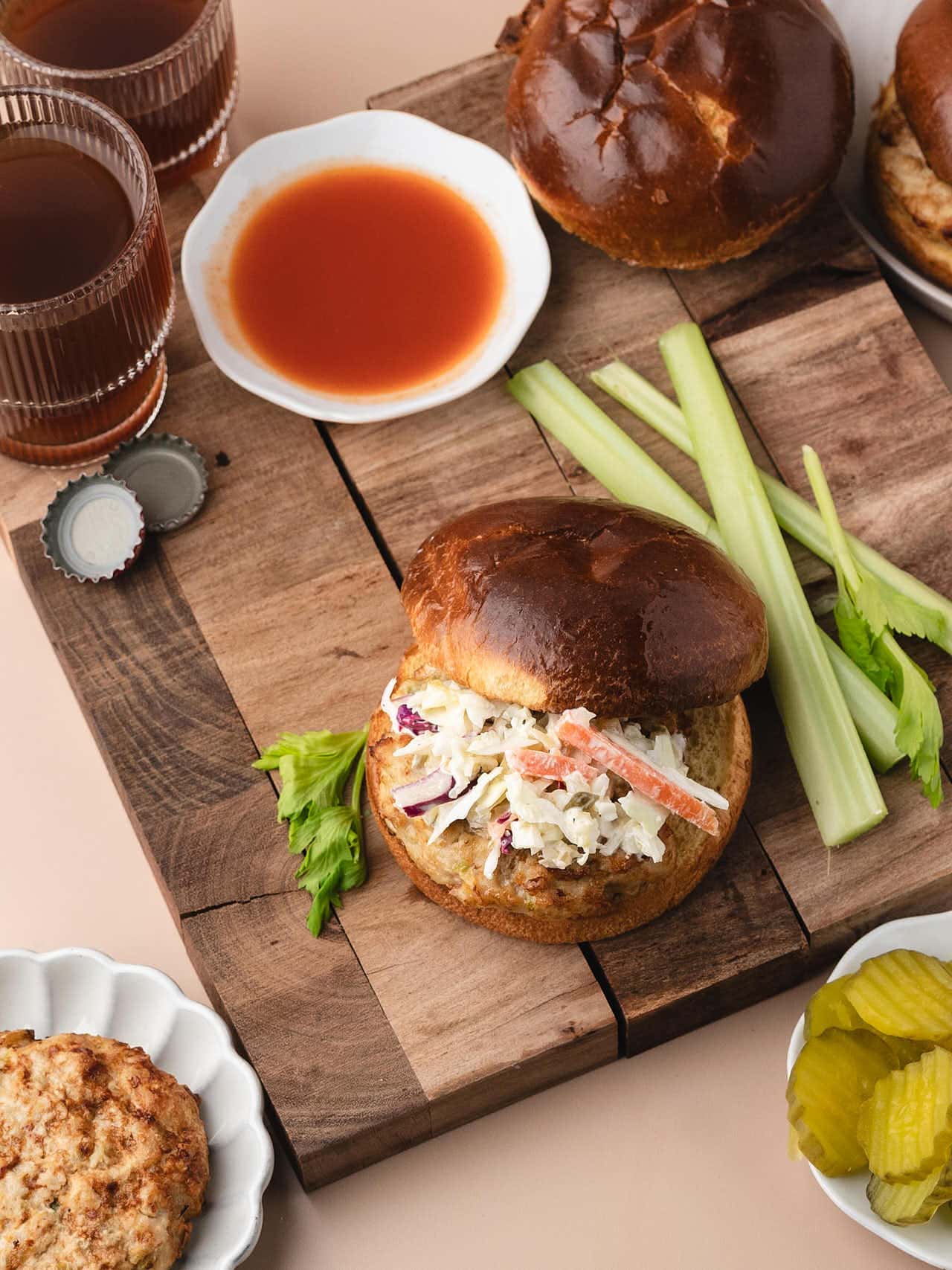 Top-down view of a Buffalo Chicken Burger with coleslaw and crisp pickles.
