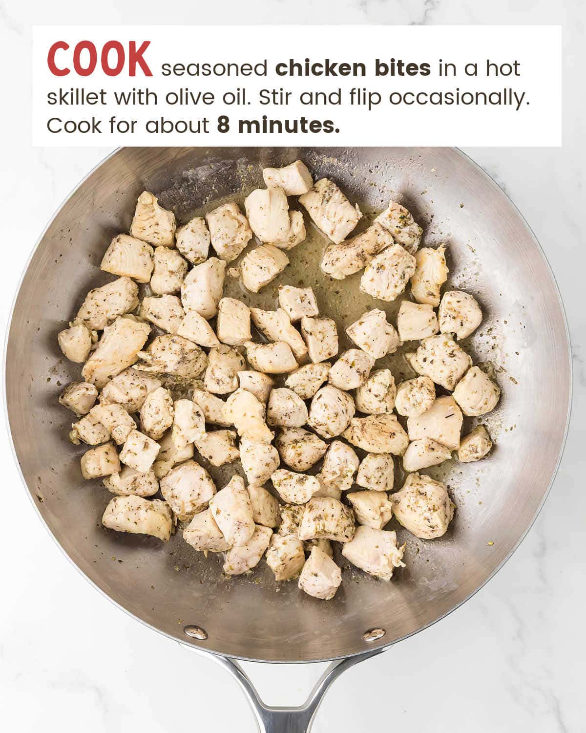 Seasoned chicken pieces cooking in a single layer in a stainless steel skillet for Garlic Butter Chicken Bites.