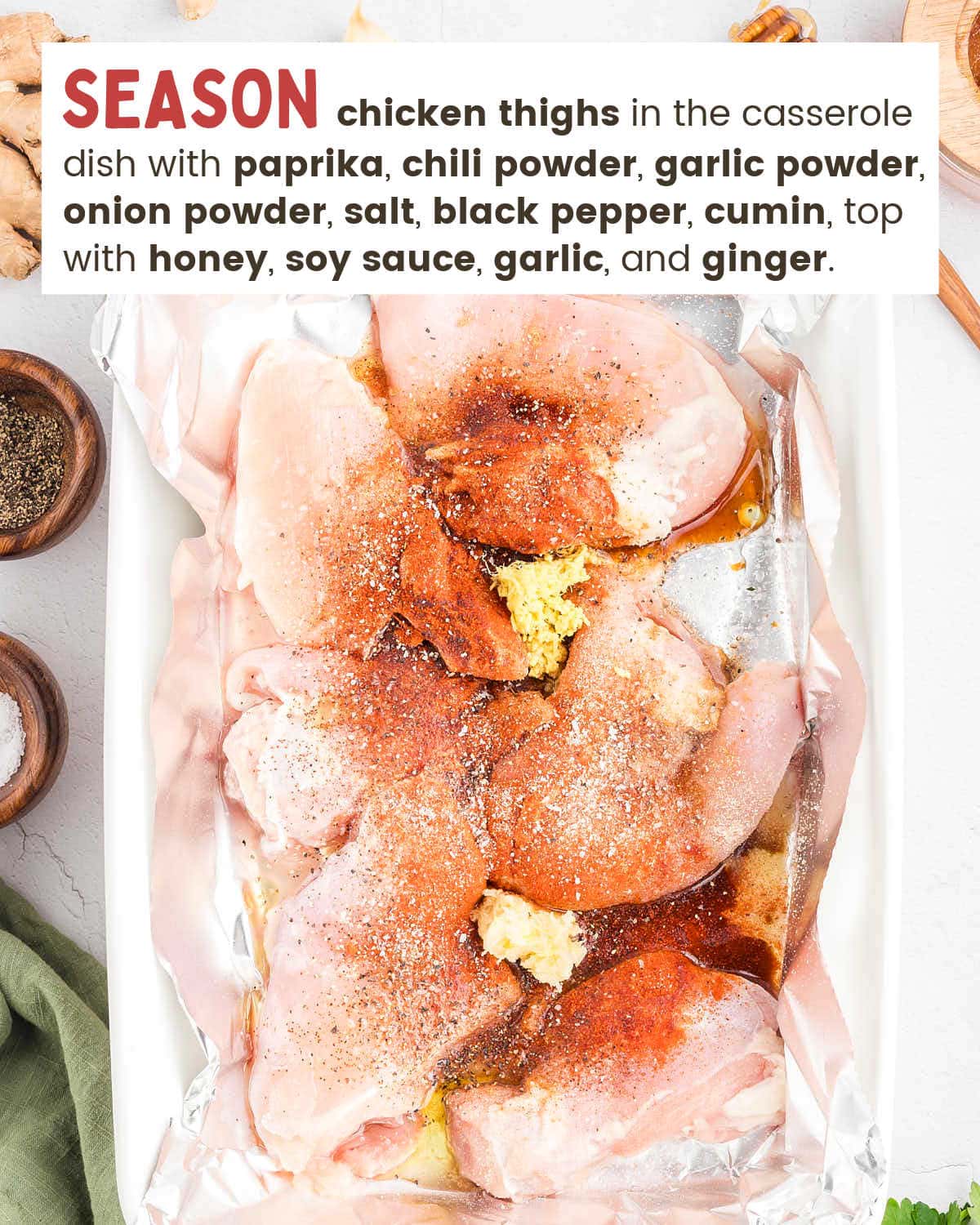 Chicken thighs in a foil-lined dish topped with the dry seasonings, honey, soy sauce, and grated ginger before tossing.