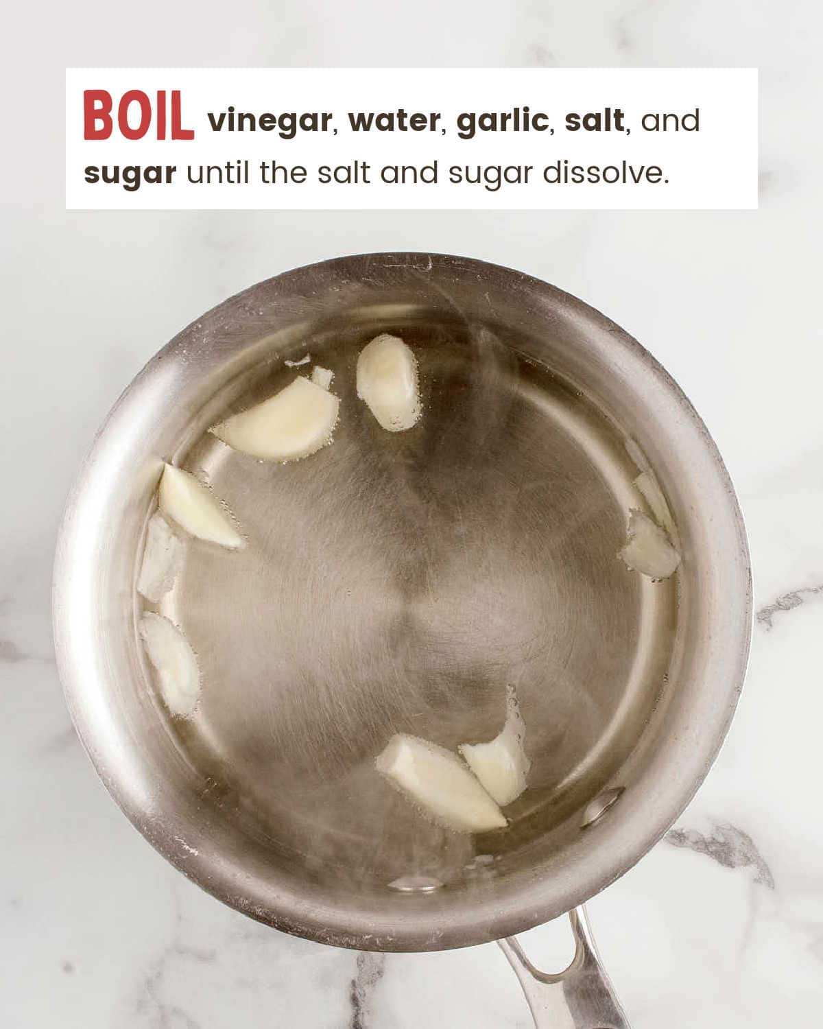 Halved garlic cloves simmering in a vinegar brine.