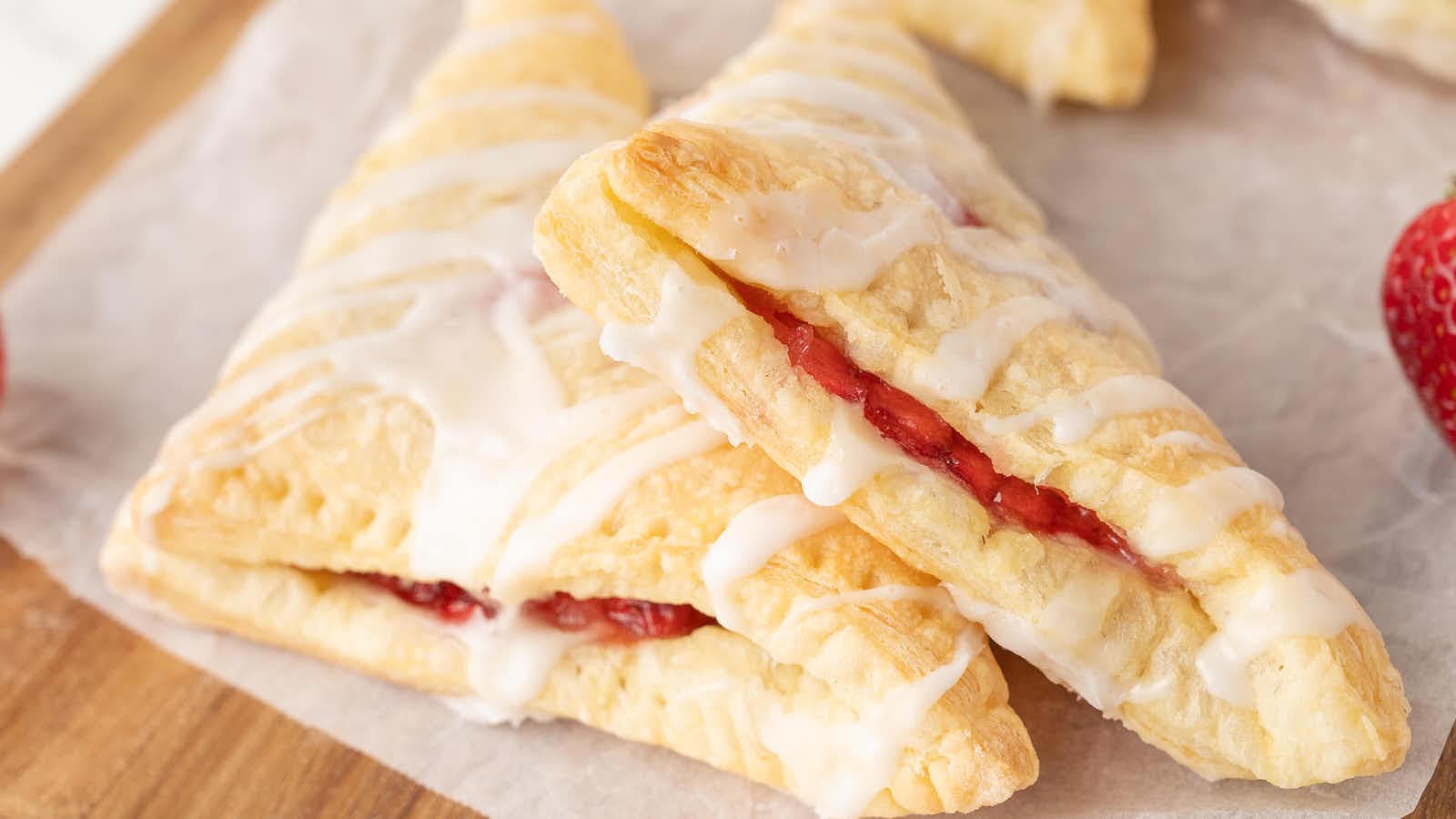 Close-up of two stacked Strawberry Turnovers with icing and visible strawberry filling.